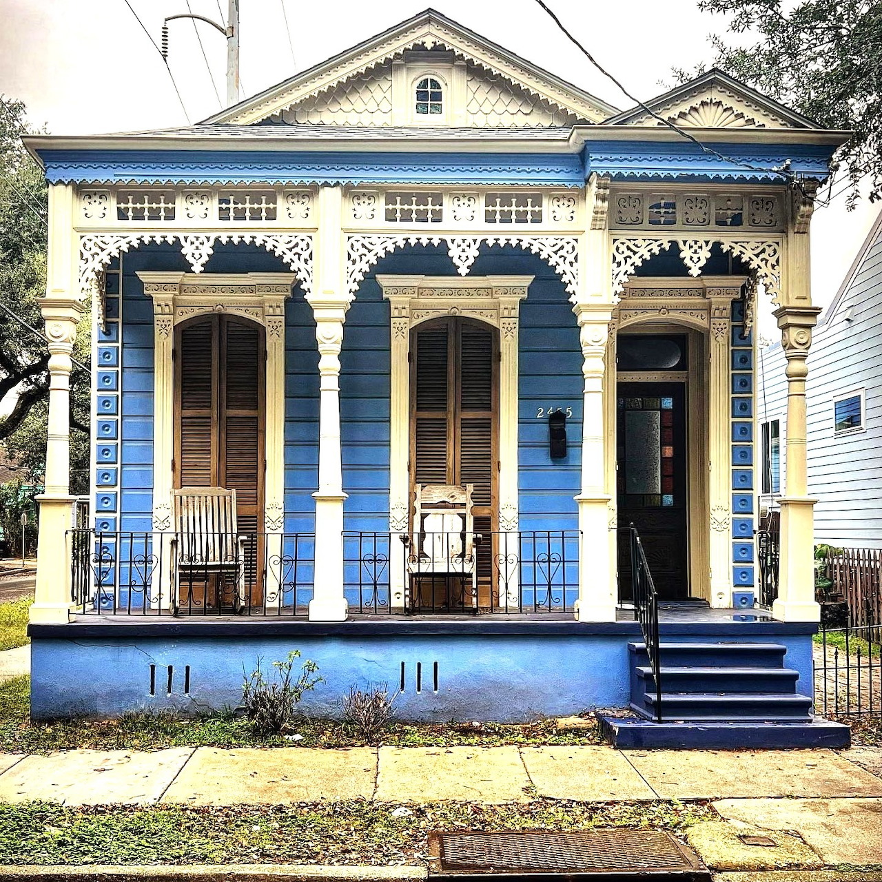 Blue Victorian gingerbread house with white ornate trim and three arched doorways