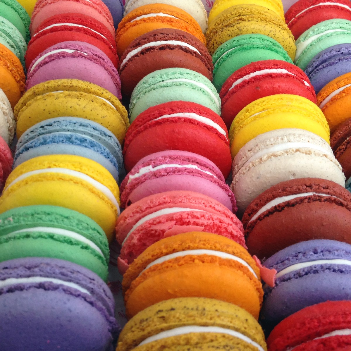 Colorful French macarons stacked in diagonal rows showing various flavors and rainbow colors