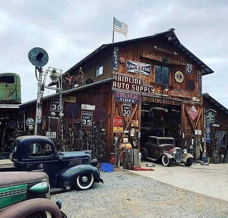 Rustic auto supply building with vintage cars and old signs outside