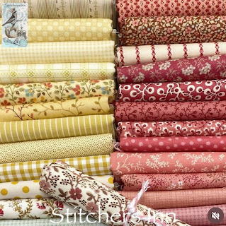 Two stacks of rolled fabric bolts in yellow and red patterns including florals, checks, and dots