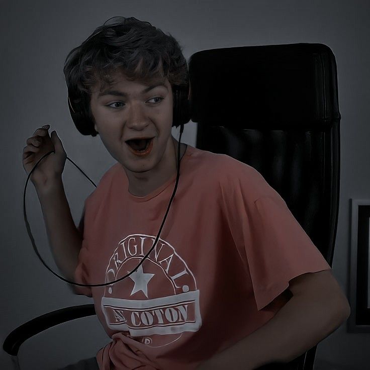 Surprised young person wearing headphones while sitting in a chair indoors