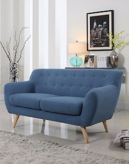 Blue tufted mid-century modern sofa with wooden legs in a white living room