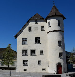 White castle with round towers and pointed roofs in town square