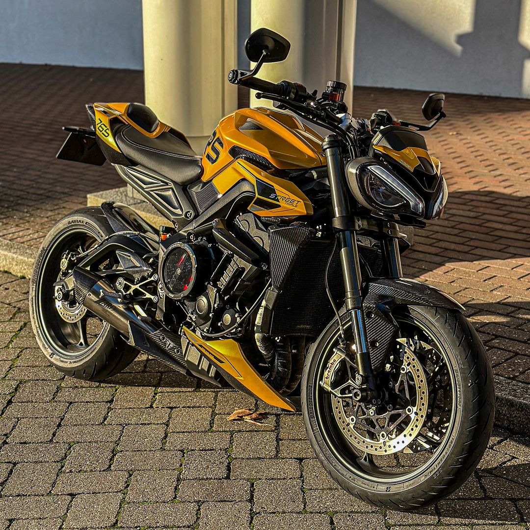 Yellow and black sport motorcycle parked on a brick-paved driveway