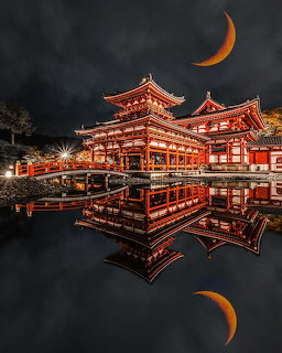 Illuminated Japanese temple reflected in calm water at night beneath a dark sky and crescent moons
