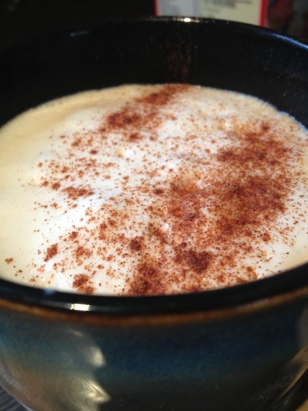Close-up of a latte with foam and spice topping in a dark blue mug