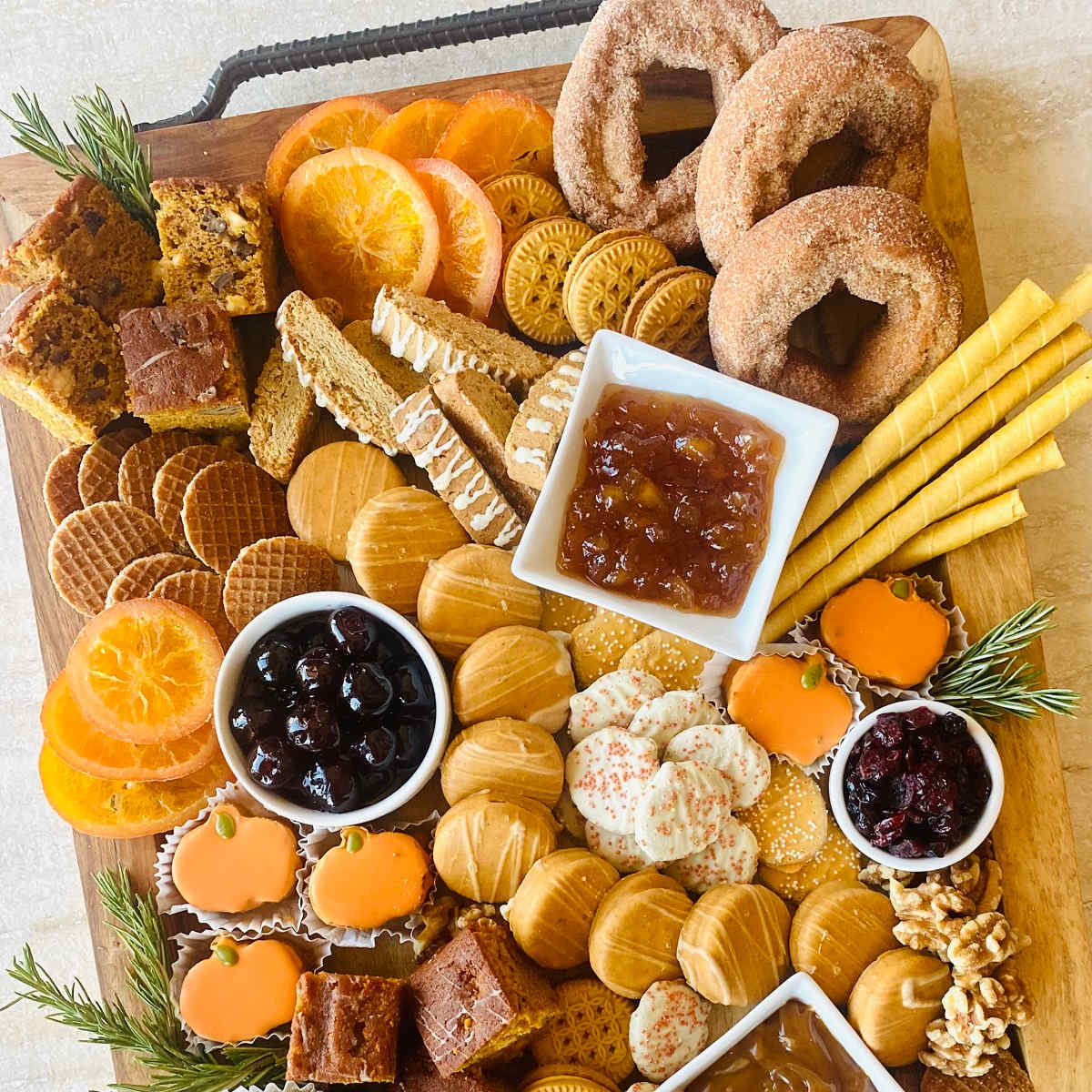 Autumn charcuterie board with cheeses, crackers, fruits, jams and pretzels on wooden serving board