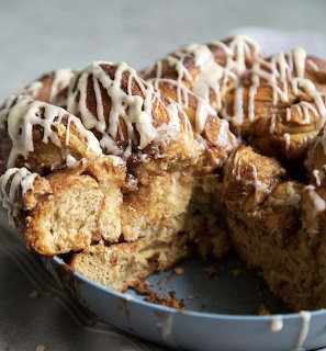 Sliced cinnamon swirl coffee cake with white icing drizzle in blue pan