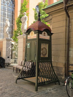 Ornate green vintage phone booth with copper roof on a cobblestone street in Gamla Stan, Stockholm