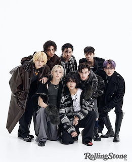 Eight young men in dark fashionable outfits posing together for a Rolling Stone photo shoot