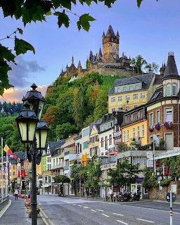 Colorful street in a European town with a castle on a wooded hill above