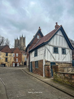 Cobbled street in Lincoln with a timber-framed house and cathedral towers in the background