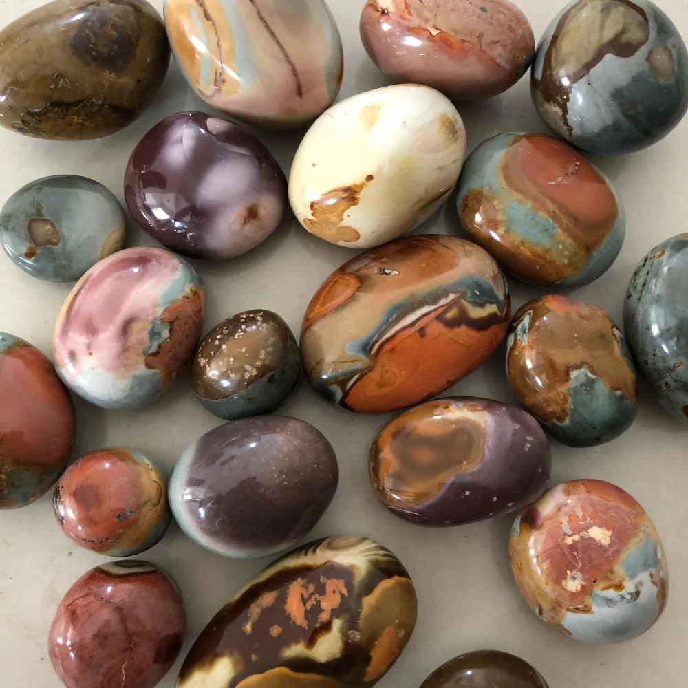 Polished mineral stones in brown, red, cream, and gray tones on a light surface