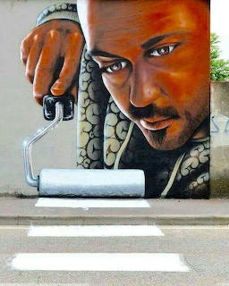 Street art mural of a man holding a paint roller that appears to paint a zebra crossing on the ground
