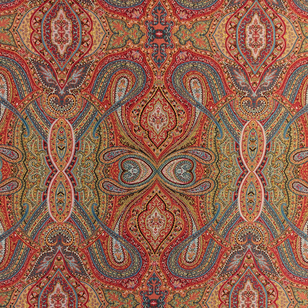 Ornate Moroccan upholstery fabric with paisley and geometric patterns in warm red, gold, and blue tones