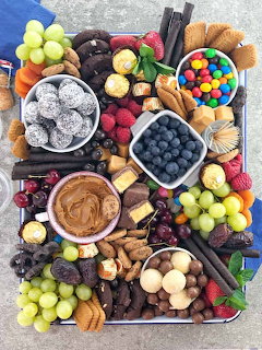 Overhead view of a colorful dessert platter with fruits, chocolates, nuts, and sweets arranged on a wooden board