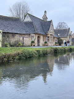 Stone cottages beside a calm canal with water reflections in a village setting