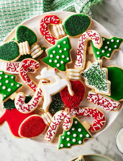 Decorated Christmas sugar cookies in festive shapes with red, green, and white icing on white plate