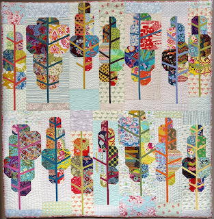 Quilt with geometric patchwork trees in vibrant patterns arranged in two rows on pale background
