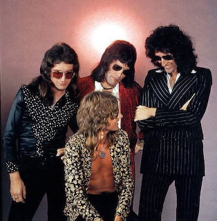 Four young men in 1970s rock clothing posing in a studio portrait