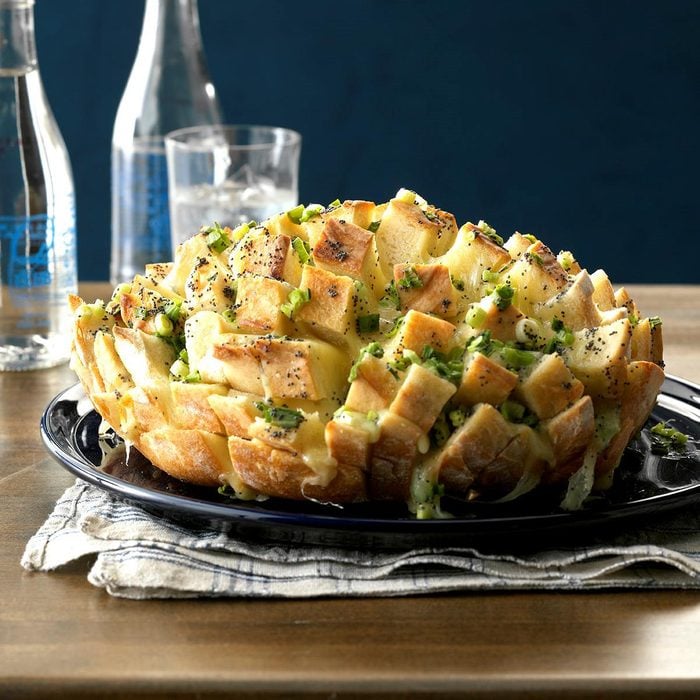 Pull-apart bread with cheese and herbs on black plate