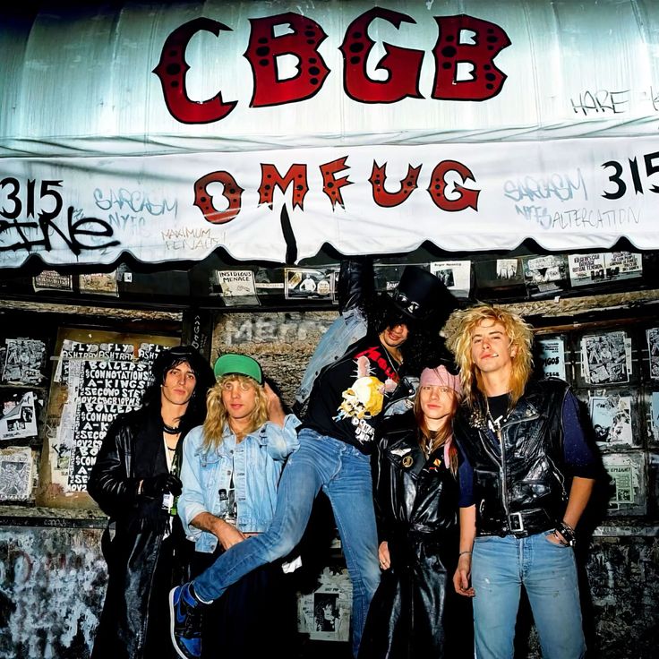 Guns N' Roses posing outside the CBGB club entrance with posters and graffiti