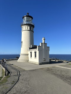 White lighthouse on a coastal cliff with clear blue sky and ocean in the background