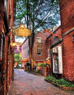 Brick alley between red brick buildings with trees and shopfronts in Portsmouth, New Hampshire