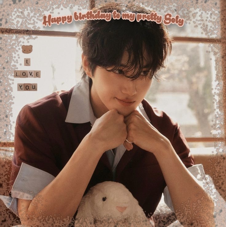 Young man in a burgundy shirt holding a small white plush toy indoors