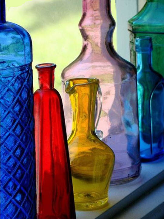 Colorful translucent glass bottles in various shapes and sizes with light shining through them