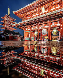 Illuminated Sensoji Temple and pagoda at night reflected on wet ground in Tokyo