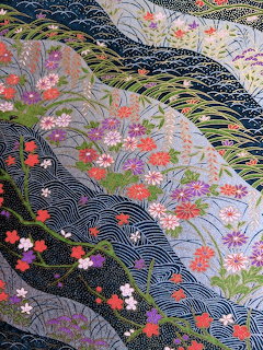 Japanese decorative pattern with wave motifs, autumn flowers, and grasses in blue, pink, green, and gold