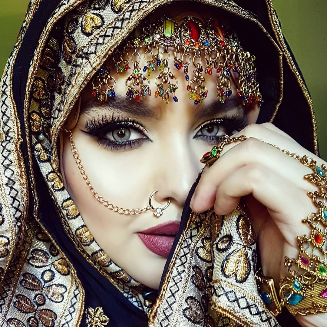 Close-up portrait of woman in ornate jeweled headscarf with dramatic makeup and jewelry
