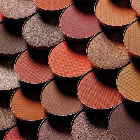 Overhead view of overlapping circular eyeshadow pans in shades of bronze, rust, and brown