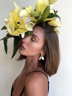 Woman in profile wearing large white and yellow lily flowers as headpiece