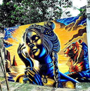 Colorful graffiti mural of Buddha with praying hands, tiger and lion on building wall