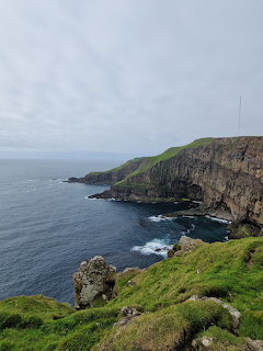 Grassy cliffs and rocky coastline above the ocean in the Faroe Islands