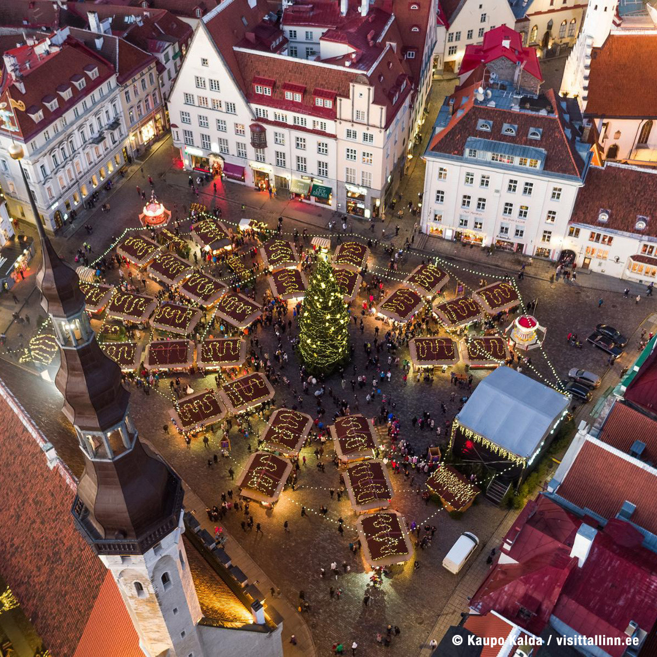 Overhead view of illuminated Christmas market in Tallinn's old town square surrounded by colorful medieval buildings