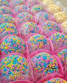 Colorful candy truffles coated in rainbow sprinkles in pink paper cups
