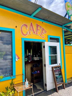 Bright yellow cafe building with turquoise accents and open entrance door