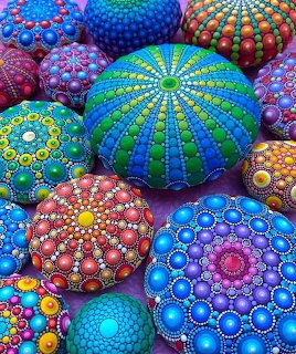 Colorful sea urchin shells painted with intricate dot mandala designs in various bright colors