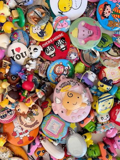 Densely packed collection of colorful kawaii toys, badges, pins, and small cartoon figurines
