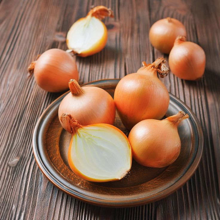 Brown onions on a rustic plate on a wooden table, including one halved onion
