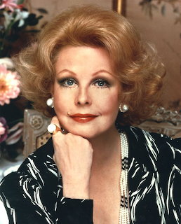 Portrait of Arlene Dahl with blonde hair, pearl earrings, and a black patterned top