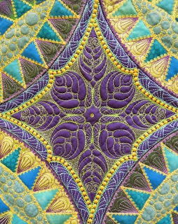 Colorful diamond quilt with purple spiral stitching, gold beading, and teal triangular patchwork pieces