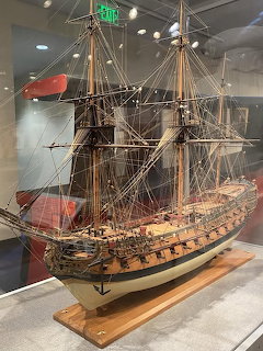 Detailed model of a tall ship with masts and rigging displayed in a museum case