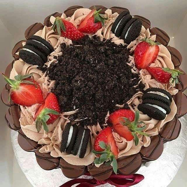 Round chocolate cake decorated with strawberries, Oreo cookies, and chocolate crumbs, viewed from above