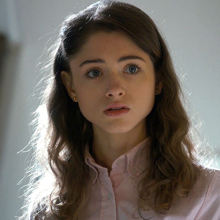 Portrait of young woman with long brown hair and blue eyes in pink shirt