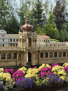 Miniature model of an ornate baroque palace with colorful flowers in foreground at a miniature park