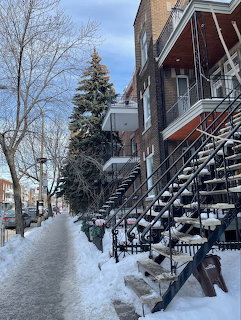 Snow-covered outdoor staircases on brick row houses along a Montreal winter sidewalk